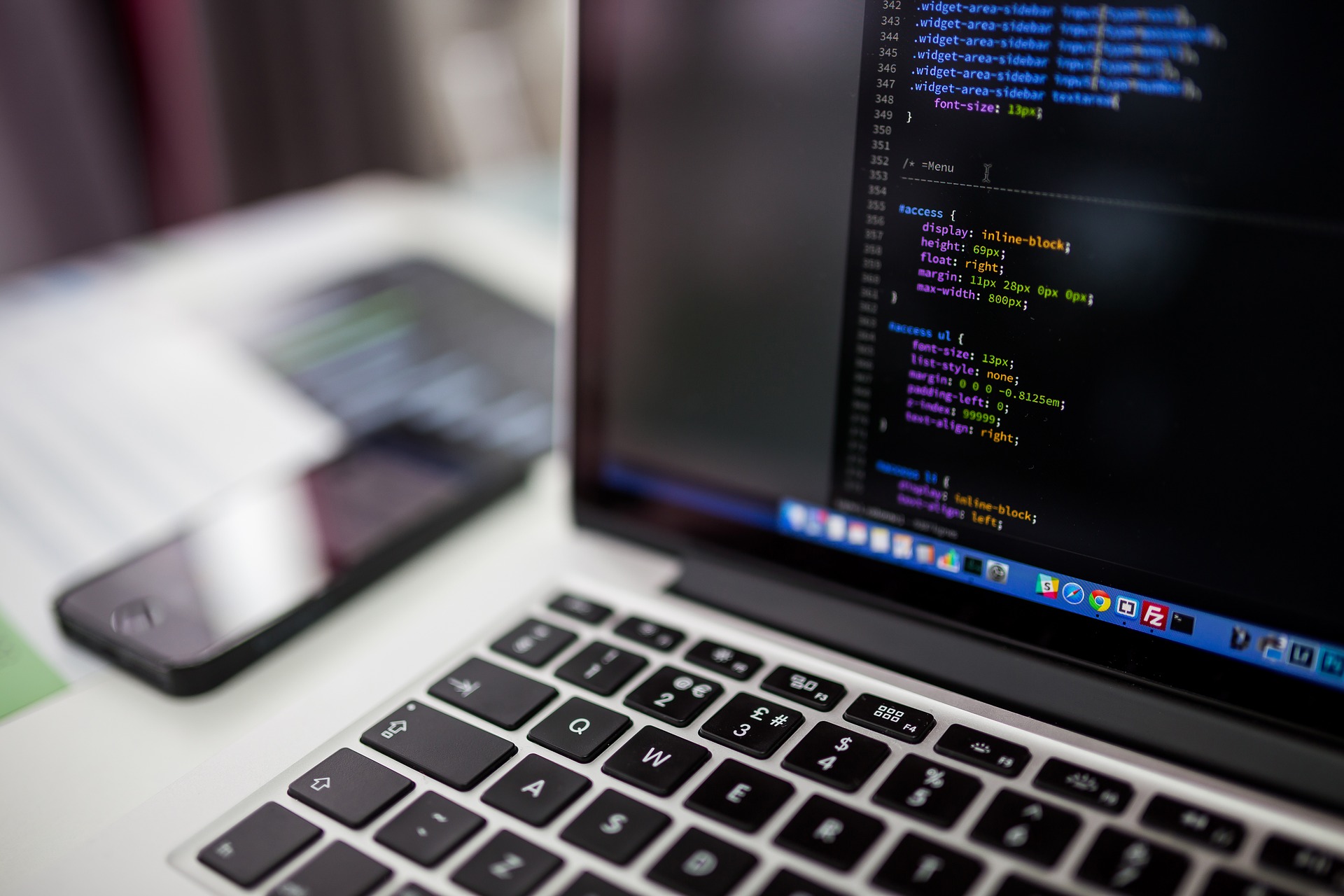 a computer with some coding and a cellphone on a desk